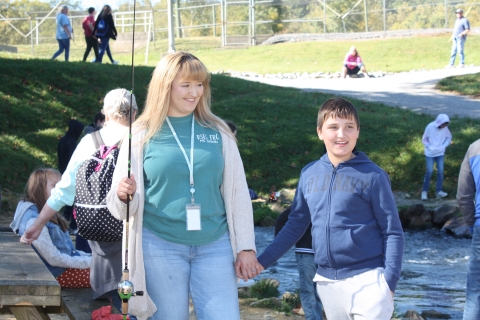 Teacher and student pictured with fishing gear at a stream