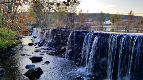 a waterfall pours over the edge of a dam against the backdrop of the city 