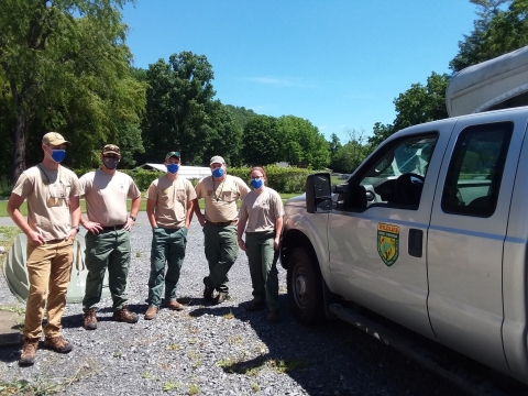 five people stand together near a truck