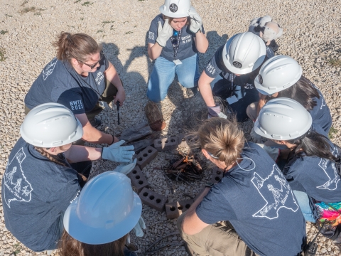 group sits in circle around campfire