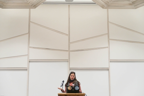 Woman standing behind a podium, looking at a computer set on the podium