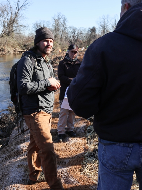 Three people standing on a stream bank