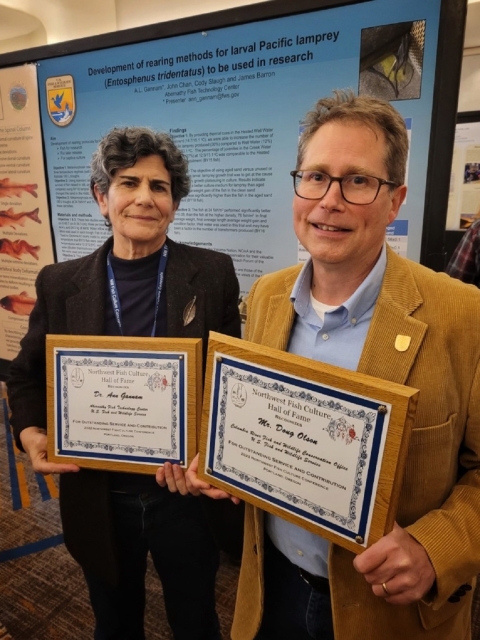 Two people smiling and each holding an award