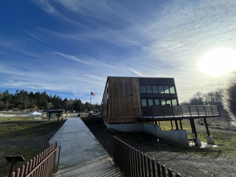 Multi-story building with elevated deck, with sunshine and American flag in the background.