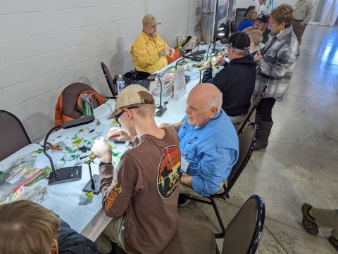 Older man teaching a young boy how to tie a fly