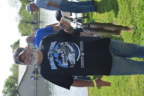 Man holding up the 4 trout he caught