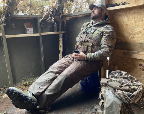 Man in camouflage sitting against a wall