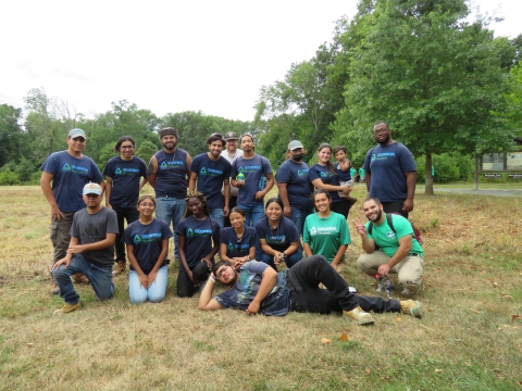 a large group of youth wearing purple and green shirts that read "Groundwork Elizabeth" stand in a natural park