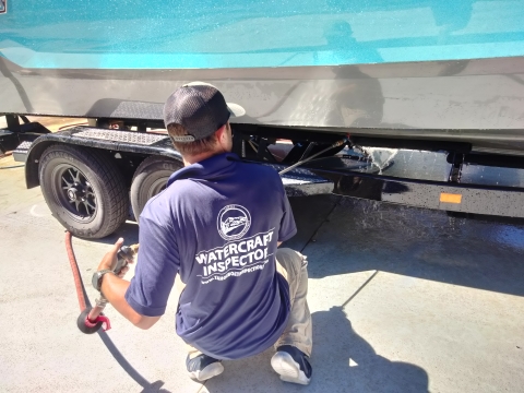 A watercraft inspector helps with hosing down a boat.