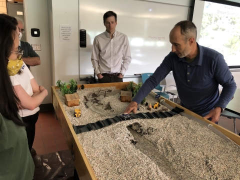 Table with gravel and layout mimicking a stream with people gathered around it