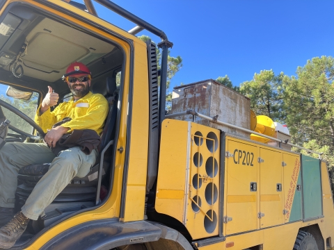 firefighter sitting behind wheel of big vehicle gives thumb's up