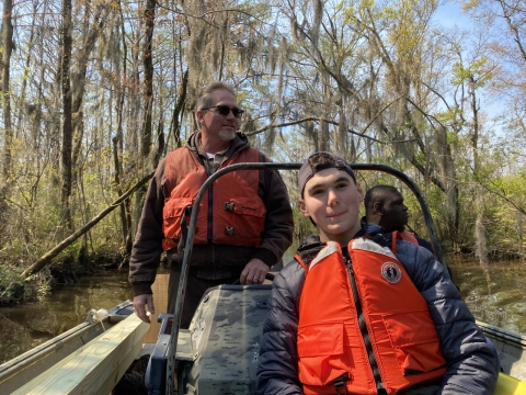 Three people ride in the back of a boat