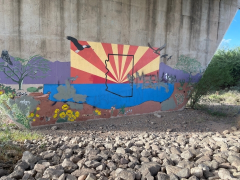 Mural of the Arizona state flag with insert of outline of Arizona on bridge underpass.