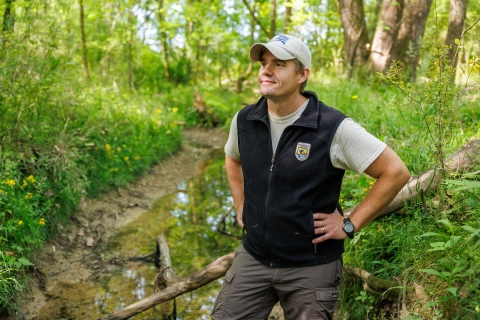 Person standing in a small creek surrounded by green vegetation