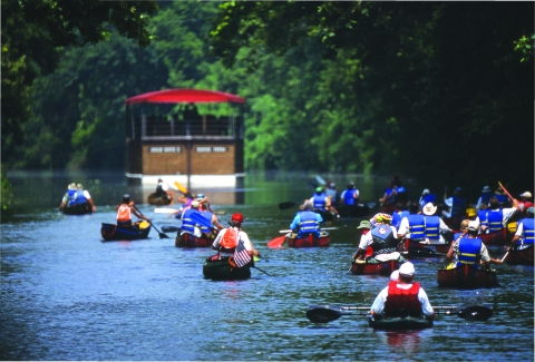 A group of kayakers paddle down a river