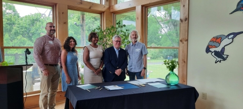 A group of five people stand behind a table.