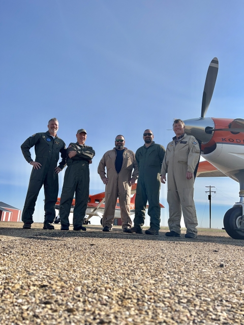 five people standing in front of an airplane