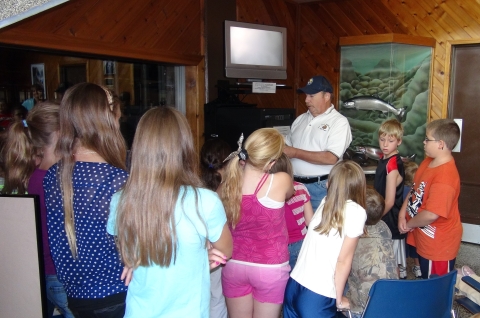 An Adult talking to a group of school children inside the Dworshak NFH