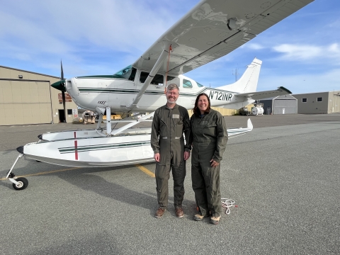 two people standing in front of an airplane