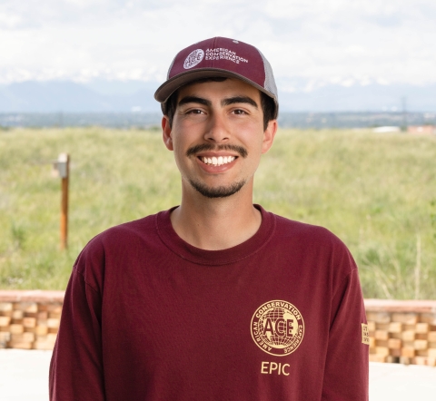 smiling man in red ACE hat and tshirt