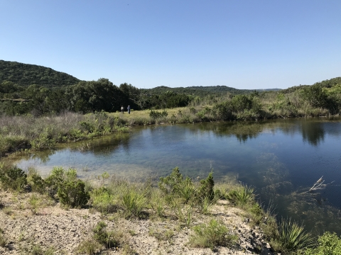 A large pool of water in a green, hilly landscape