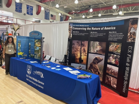 USFWS employee next to informational booth at event