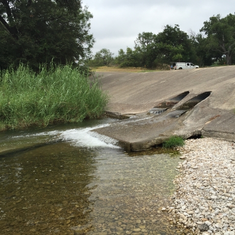 Two culvert-like holes in a cement road crossing with low water flow