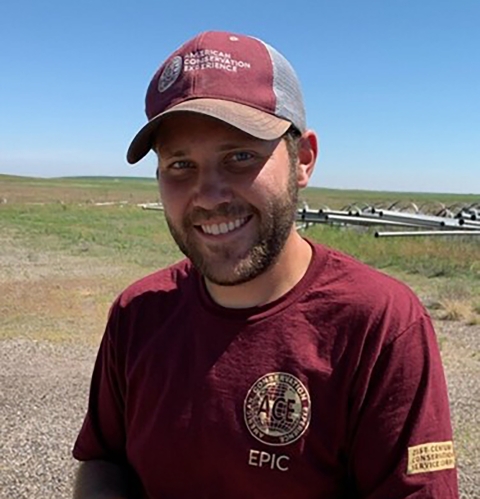 smiling man in an ACE tshirt and hat