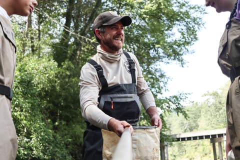 Smiling person holding a small net by the handle standing between two other people