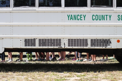 Students standing in a line behind a school bus