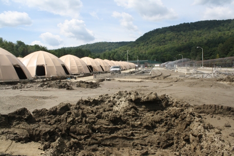 Thick mud and sediment covers the ground around the canvas-domed rearing tanks at the fish hatchery.