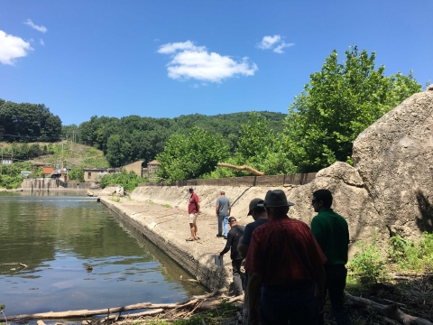 People standing on concrete dam in front of water