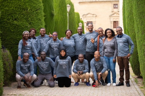 A group shot of international students on a brick path with green trees on either side.