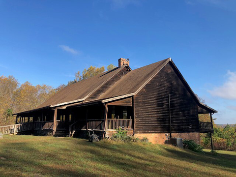 a brown, wooden building on a grassy hill