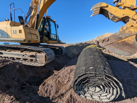 A piece of heavy equipment moves a mat onto a boat ramp.