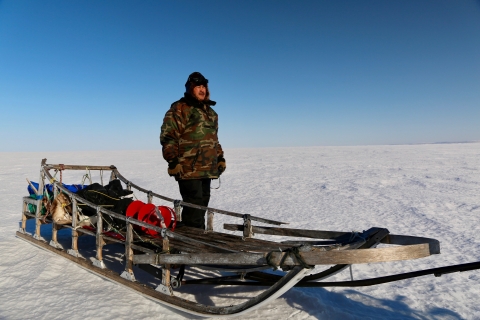 man standing by a sled on snow