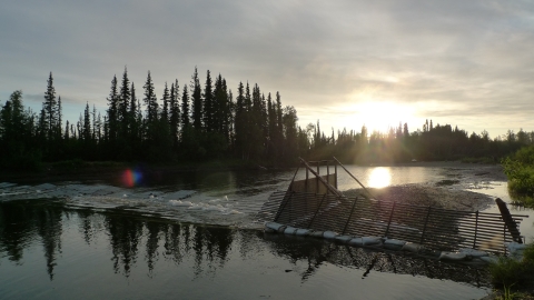 A weir across a river with low sun