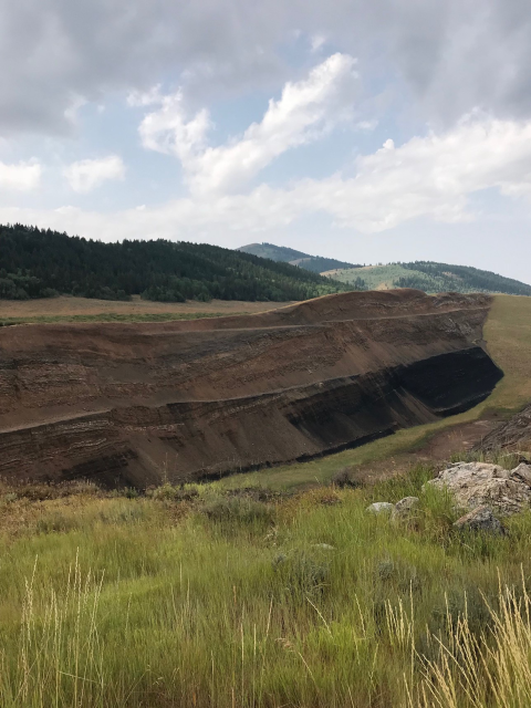 An open pit mine, surrounded by green vegetation