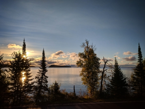 The sun rises over the tree lined shores of Lake Superior