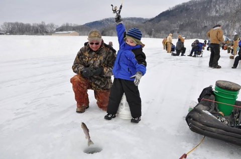 Young boy enjoying icing as he holds up his catch. 