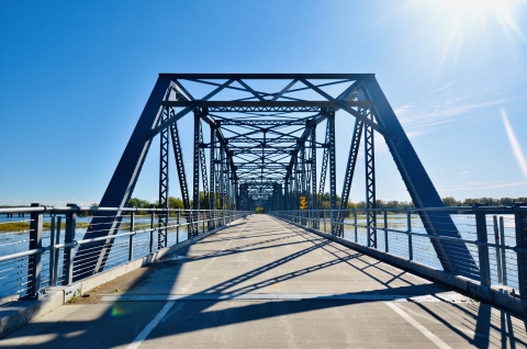 Bridge with a paved pedestrian trail over a lake on a sunny day