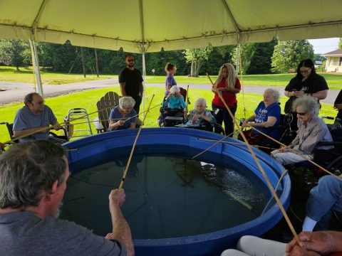 Elderly people fishing out of tub with cane poles