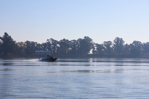 A boat is pictured in the middle of a tree lined river