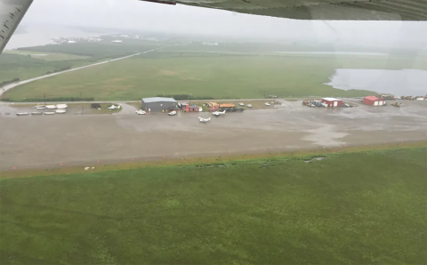 small planes and buildings next to a gravel runway