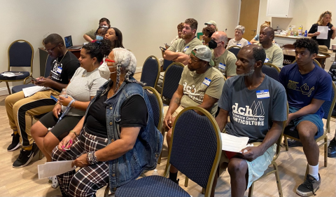 More than a dozen people sit in a meeting space