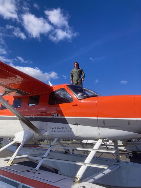 a person stands on a top of an airplane wing during a fuel stop