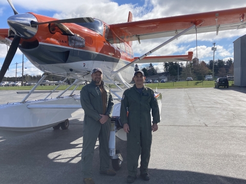 two people standing in front of an airplane