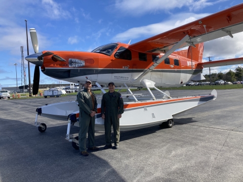 two people stand in front of an airplane