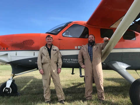 two people standing in front of an airplane