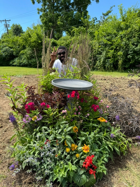 A joyful man behind his garden and birdbath